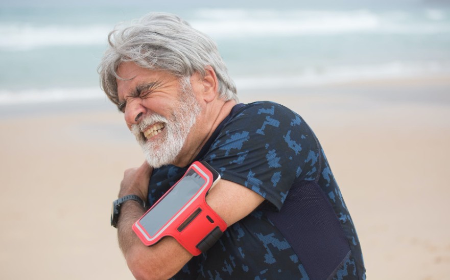 a man holding his shoulder while grimacing in pain