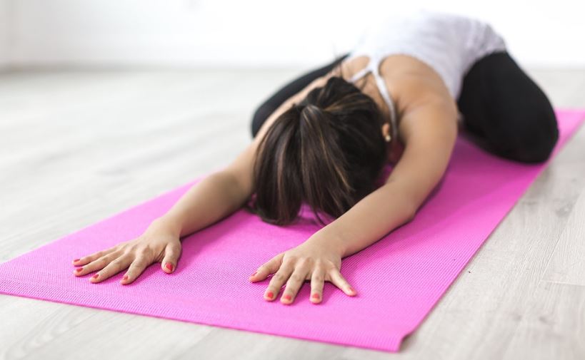 A woman stretching on a pink yoga mat
