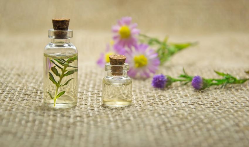 two clear glass bottles with essential oilsa and flowers