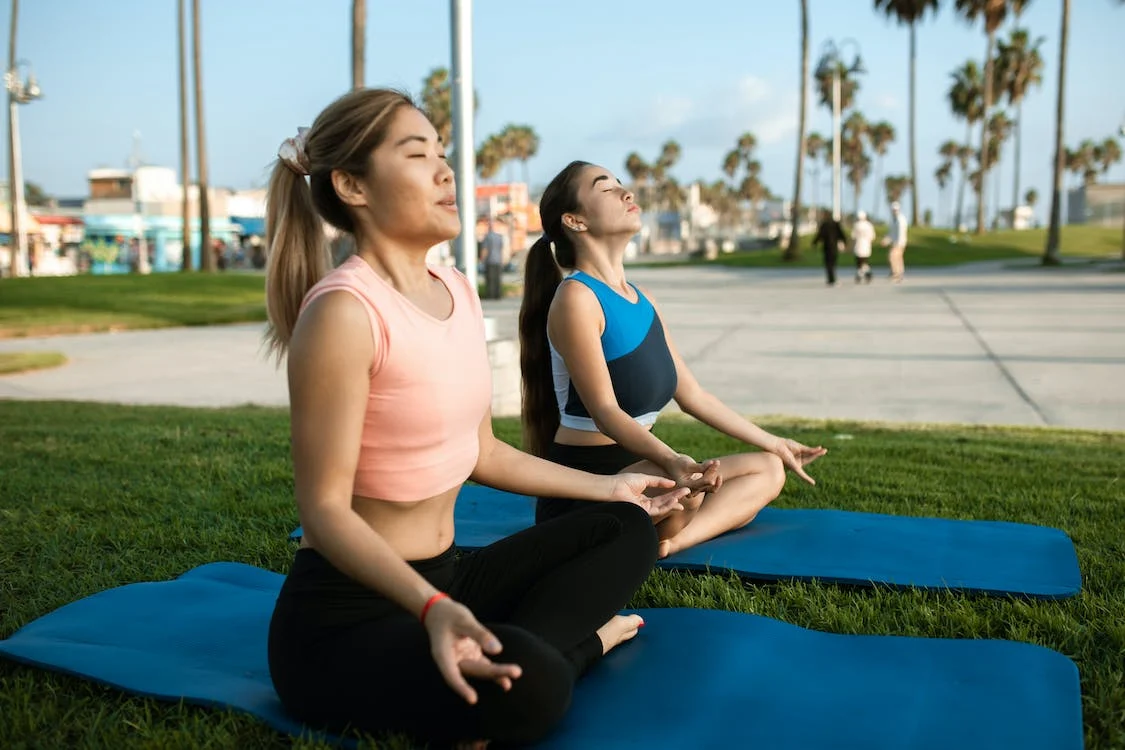 Women meditation in the park with yoga mats