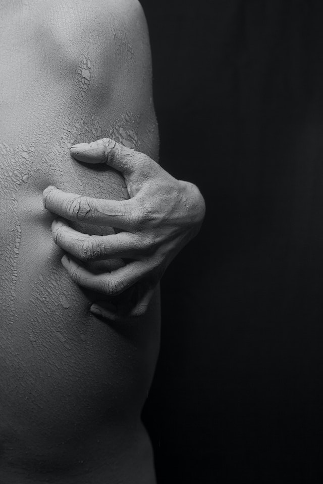 close-up photo of a person's hand scratching on his flaky skin in black and white