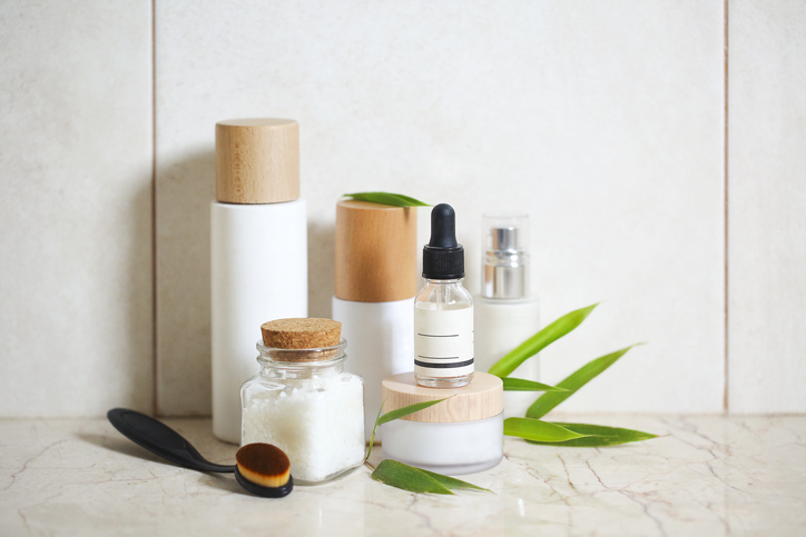 Face cream, serum, lotion, moisturizer and sea salt among bamboo leaves in the bath