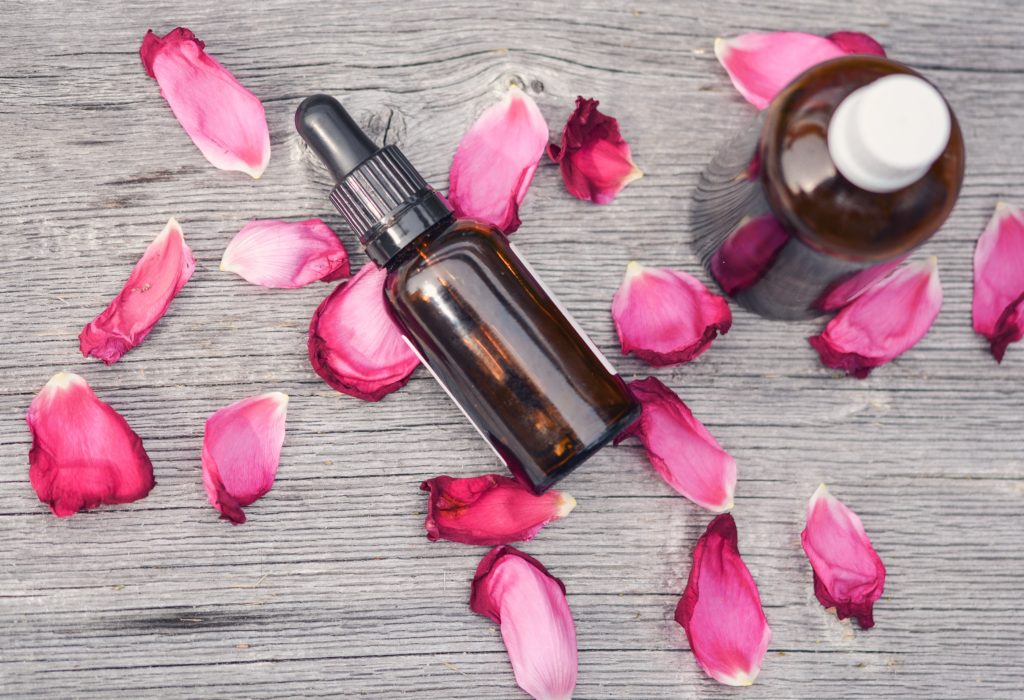 Rose essential oil bottles with surrounding rose petals