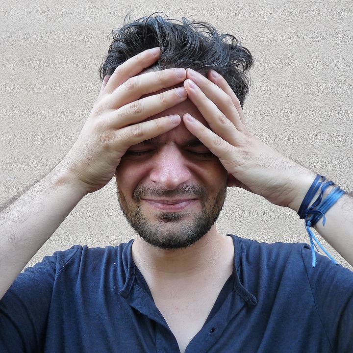 A man with headache, having both hands on his head