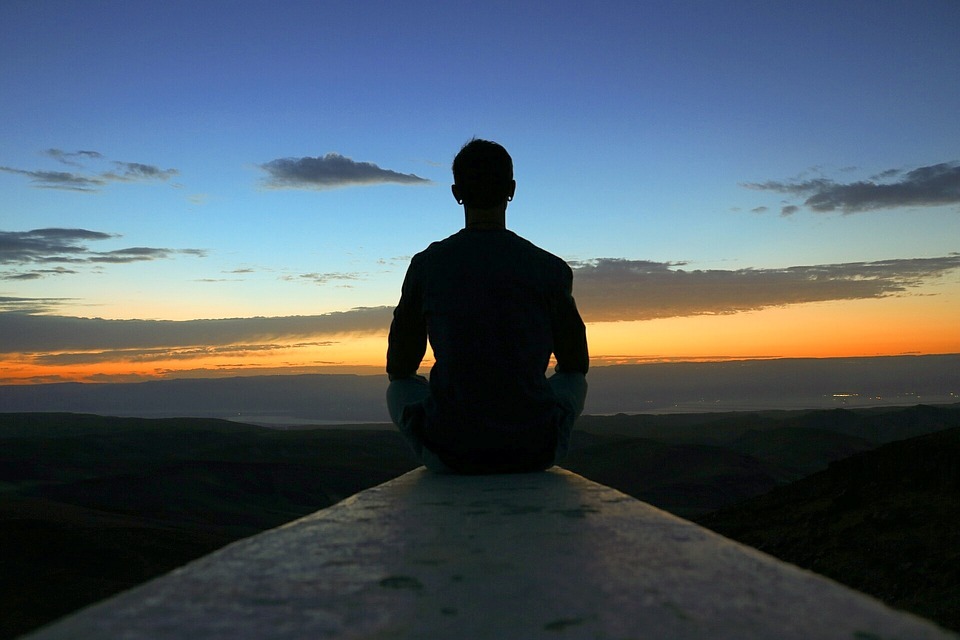 A man meditating with a sunrise view