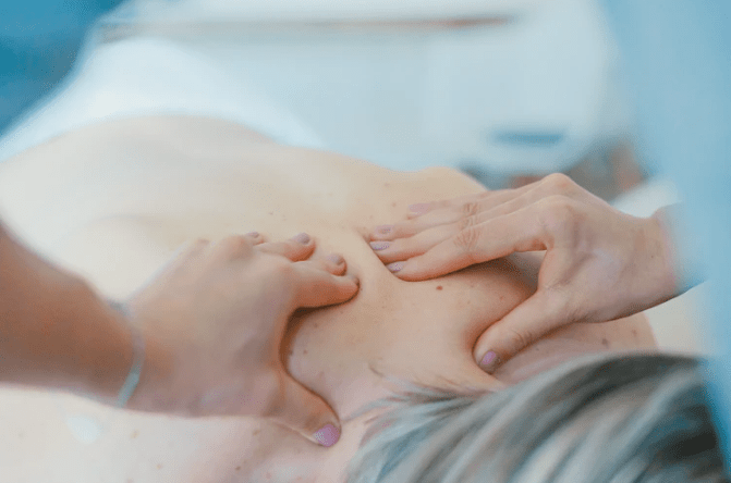 A person massaging the back of a woman