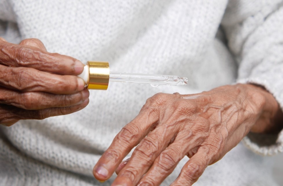 a close up of an old person holding an oil dropper above their hand