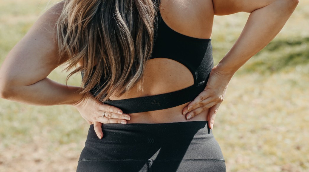 a woman in workout clothes touching her lower back