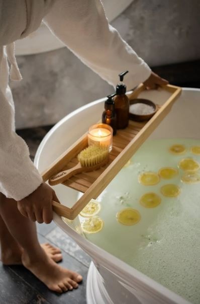 a woman preparing for her salt bath by placing a tray of bath products on her tub