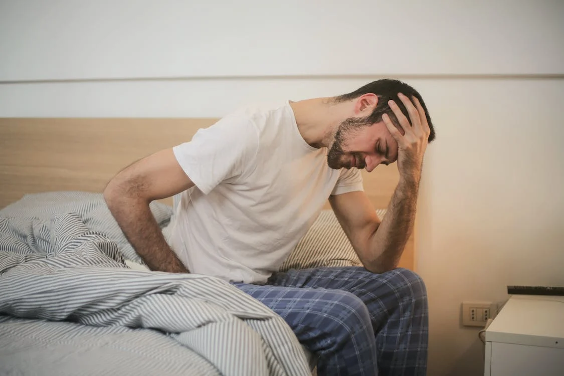 Young man in sleepwear suffering from headache in the morning