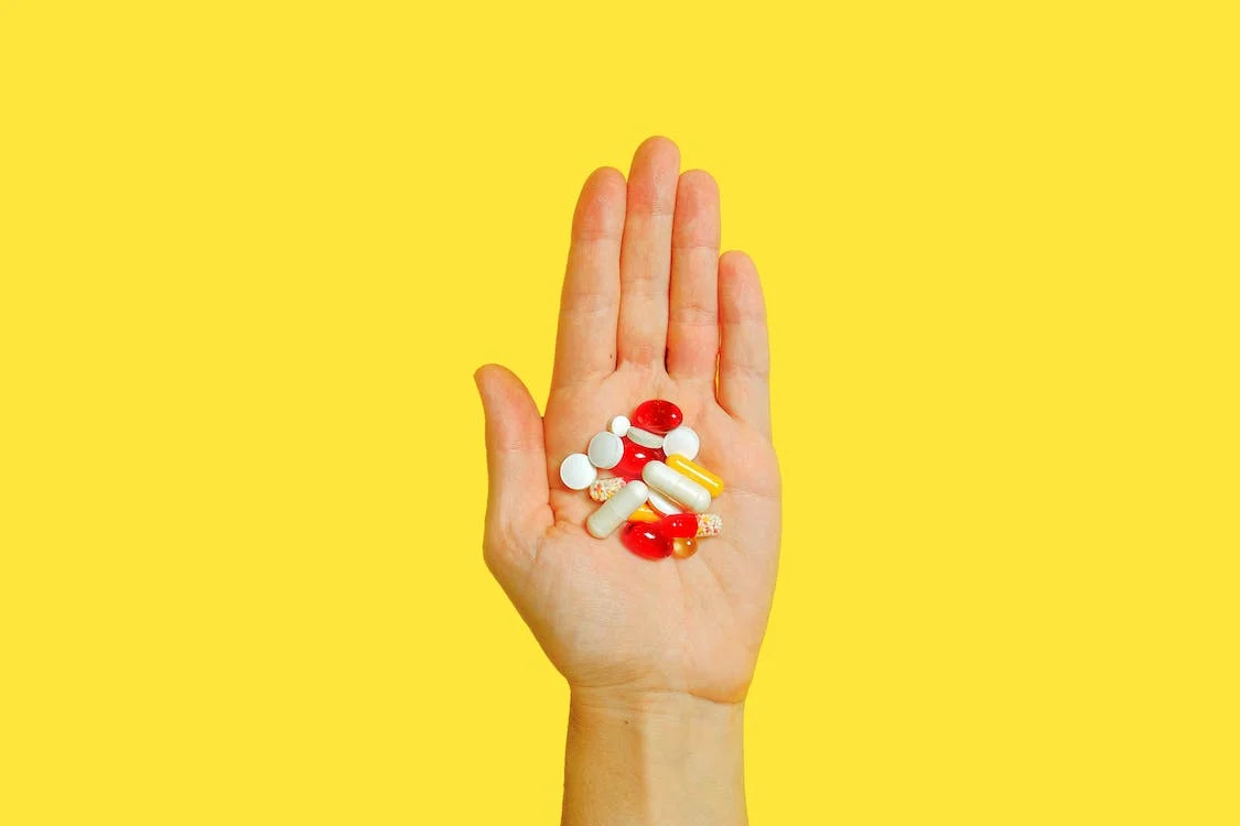 a person with a bunch of medication pills on hand