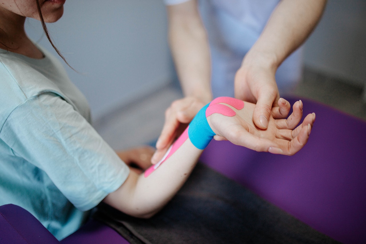 person applying kinesio tape on a girl's arm and wrist