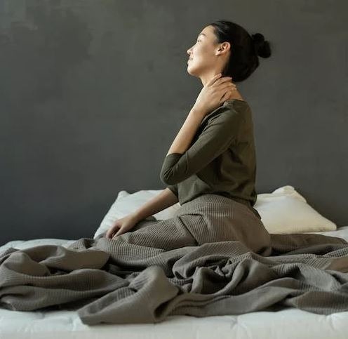 woman in gray dress sitting on bed